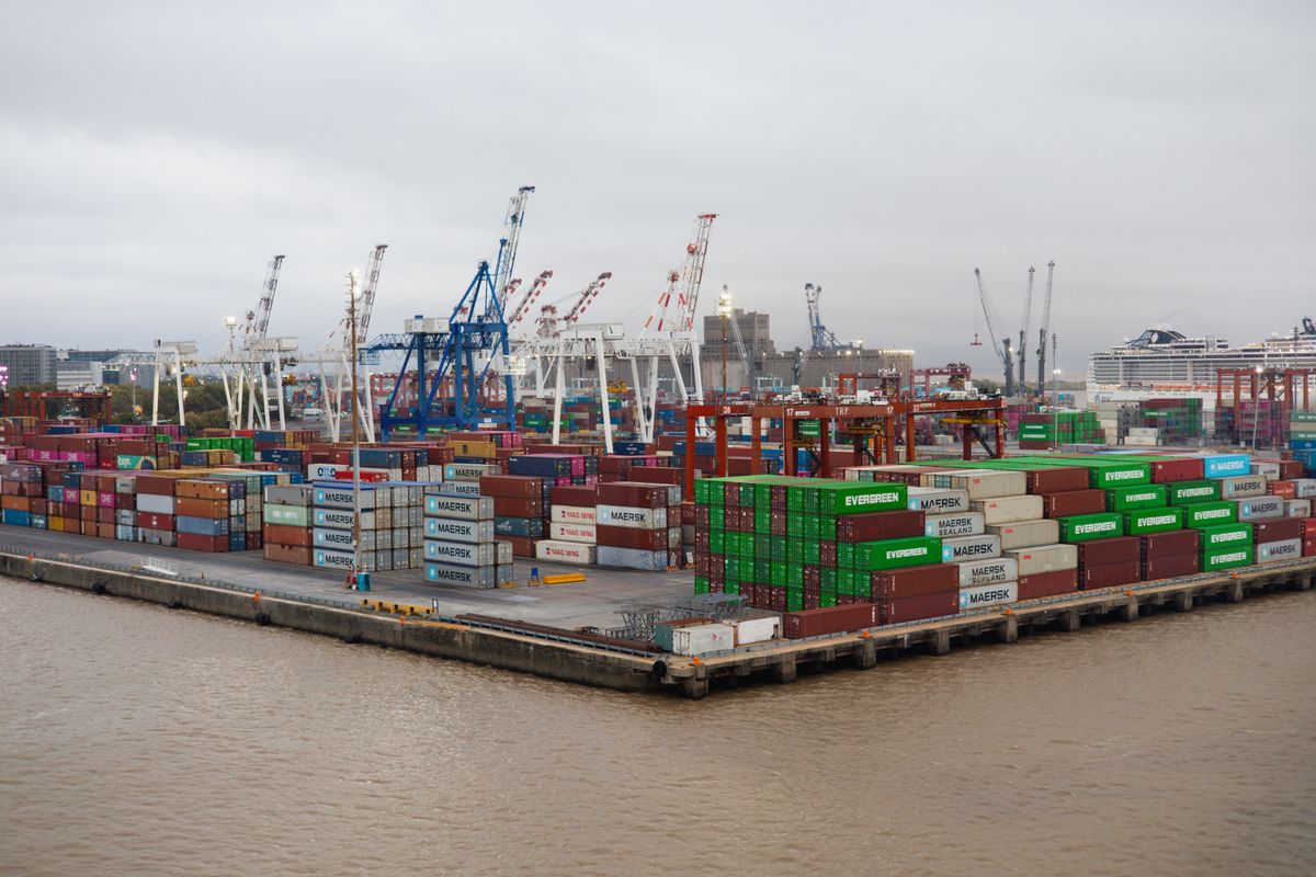 Stacked shipping containers and gantry cranes at a busy container port